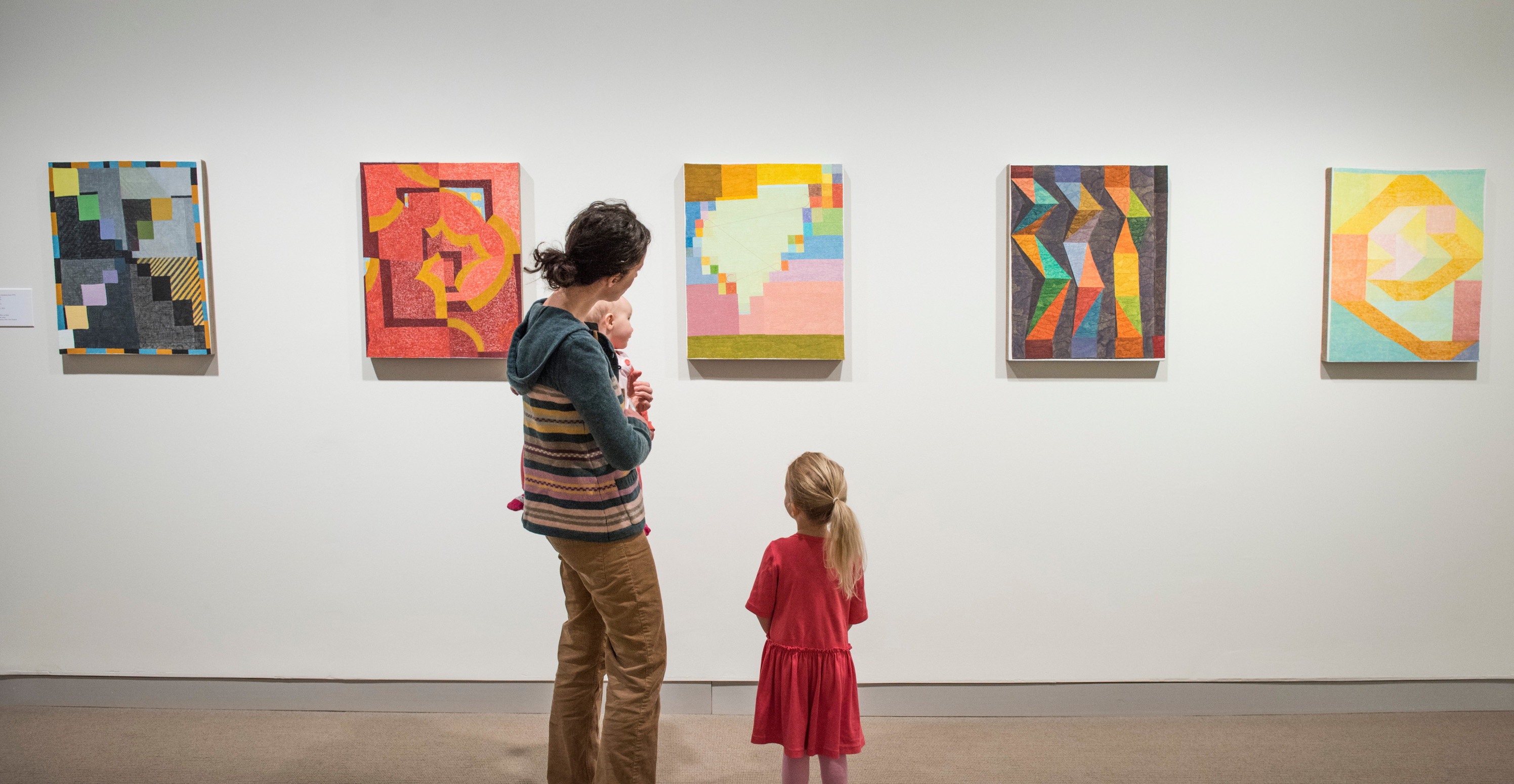 A parent and two children looking at abstract art on the wall