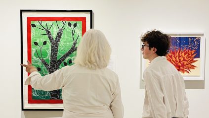 An adult woman and young man look at pieces of art on the walls at the Zillman